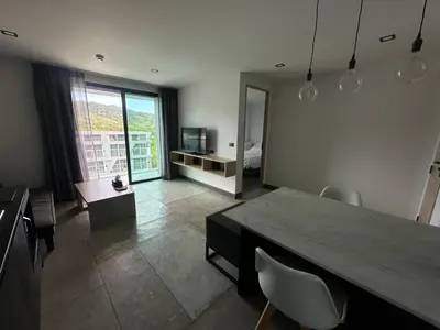 a living room with a table and chairs and a bedroom at Modern apartment on Naiharn Beach B404 in Rawai Beach