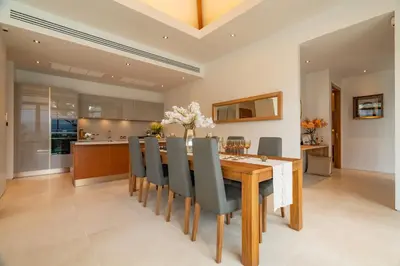 a kitchen and dining room with a wooden table and chairs at Modern 3BR Pool Villa at Anchan Flora in Bangtao in Bang Tao Beach