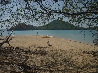 a yellow boat on a beach near the water at Pasai Beach Lodge in Ko Yao Noi