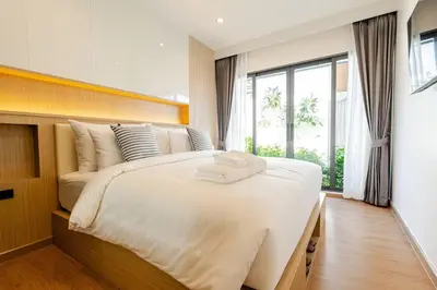 a bedroom with a large white bed with a window at Oasis by the Sea M1- House with Pool and Amenities in Phuket Town