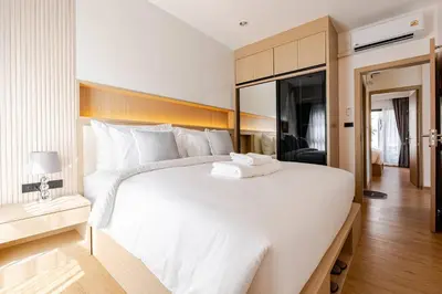 a large white bed with a towel on top of it at Oasis by the Sea M1- House with Pool and Amenities in Phuket Town