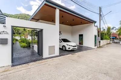 a white house with a car parked outside of it at Oasis by the Sea M1- House with Pool and Amenities in Phuket Town