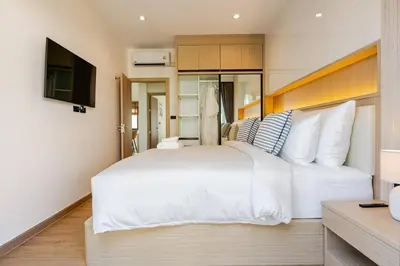 a bedroom with a large white bed and a television at Oasis by the Sea M2- House with Pool and Amenities in Phuket Town