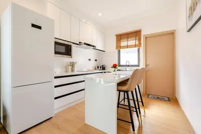 a kitchen with white cabinets and a white refrigerator at Oasis by the Sea M2- House with Pool and Amenities in Phuket Town