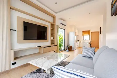 a living room with a couch and a tv on a wall at Oasis by the Sea M3- House with Pool and Amenities in Phuket Town