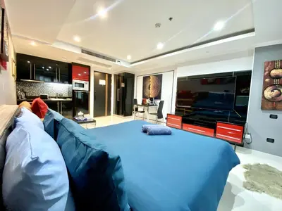 a bedroom with a large blue bed and a kitchen at Patong - Studio Condo - Absolute Bangla Unit in Patong Beach