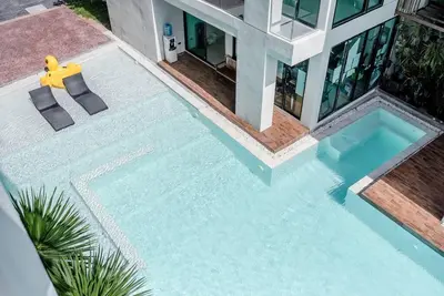 a swimming pool with two chairs and a house at Sunset Mountain View 2bedroom Patong in Patong Beach