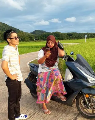 a man and a woman standing next to a motorcycle at Bung Bud Garden Bungalows & Homestay - Koh Yao Noi in Phangnga