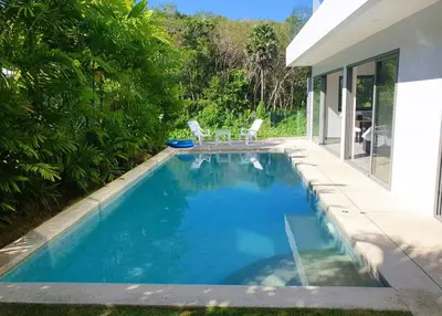 a swimming pool with two chairs and a house at Modern pool villa 3 bedrooms in Rawai Beach
