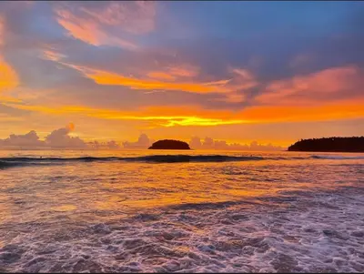 a sunset on a beach with the ocean at Ciao Bella GuestHouse & Bistro in Kata Beach