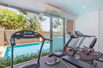 a gym with two exercise bikes and a swimming pool at Сhic condo студия с бассейном in Karon Beach