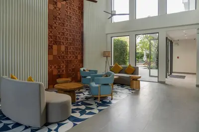 a lobby with blue chairs and tables and windows at Laguna Lakeside Apartment Phuket Bang Tao in Bang Tao Beach