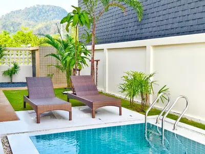 two chairs next to a swimming pool at Krabi Private Pool Villa 2 by Belcarra Spaces in Ban Khlong Haeng