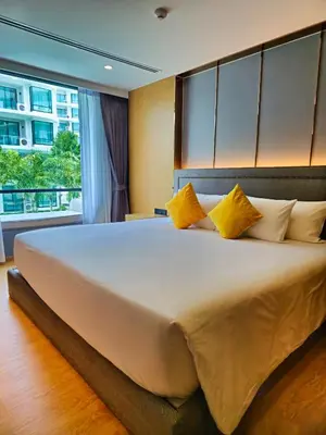 a bedroom with a large white bed with yellow pillows at Family Luxe Apartment in 5 Star hotel in Phuket Town