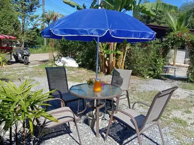 a table and chairs with a blue umbrella at Cancel in Phang-nga
