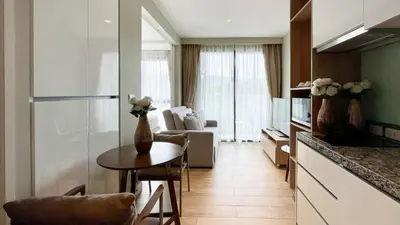 a kitchen with a table and a living room at Cozy apartment with a Resort Facilities in Bangtao in Bang Tao Beach