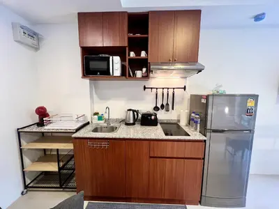 a kitchen with wooden cabinets and a stainless steel refrigerator at Mai Khao Serenity in Ban Mai Salae