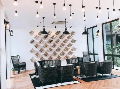 a room with chairs and a wall of books at Saturdays by Lotus Heart in Ban Saiyuan (1)