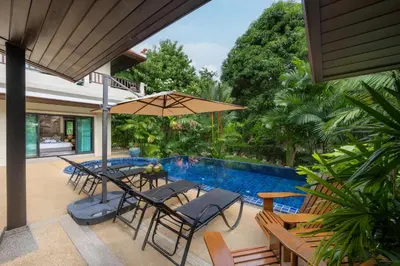 a patio with chairs and an umbrella next to a swimming pool at Meraya Villa with Private Pool Near Nai Harn Beach in Rawai Beach