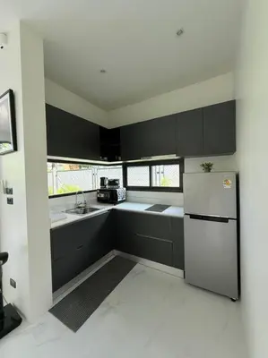 a kitchen with black and white cabinets and a refrigerator at Вилла 2 санузла, 2 спальни in Ban Suan