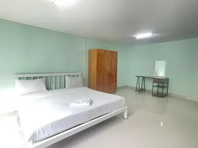 a bedroom with a large white bed and a table at SHERRY'S Guest House in Patong Beach