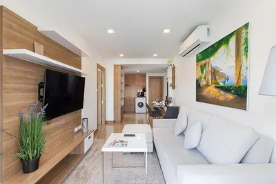 a living room with a white couch and a tv at Calypso condo in Rawai Beach