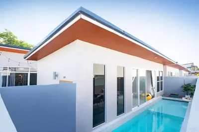 a house with a swimming pool next to a house at Best Time Pool Suites in Chalong