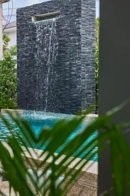 a fountain in a brick wall with a waterfall at Phuket Paradise Retreat in Phuket Town