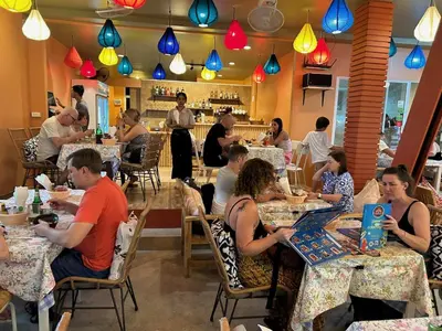 a group of people sitting at tables in a restaurant at Sugar and Spice Inn in Kata Beach