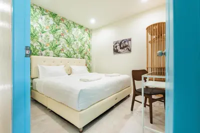 a bedroom with a bed and a desk and a chair at Songbird Suites in Ban Khlong Haeng
