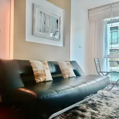 a black leather couch in a living room with a window at DREAMS APARTMENTS by ART PATONG RESIDENCE in Patong Beach