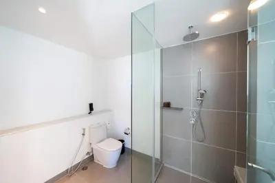a bathroom with a glass shower and a toilet at Karon Seaview Beachfront - 2 BR Apartment At Paradox Residence in Karon Beach