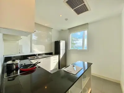 a large kitchen with a black counter top at Karon Seaview Beachfront - 2 BR Apartment At Paradox Residence in Karon Beach