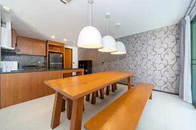 a kitchen with a wooden table and a bench at The fin villa rawai 2 bedroom in Ban Saiyuan (1)