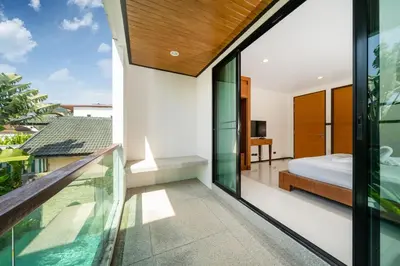 a bedroom with a balcony with a bed and sliding glass doors at The fin villa rawai 2 bedroom in Ban Saiyuan (1)