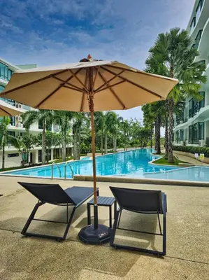 a table and two chairs under an umbrella next to a pool at New stylish studio in La Vita 5 in Rawai Beach