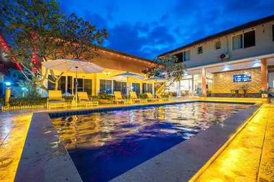 a pool with chairs and umbrellas next to a building at Tongtong Garden Holiday Hotel\u666e\u5409\u5c9b\u901a\u901a\u82b1\u56ed\u9152\u5e97 in Rawai Beach