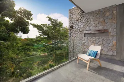 a white chair sitting on a balcony with a stone wall at Private & Modern 4BR Pool Villa Otero, 3 Levels of Comfort with Greenery Views, Kamala in Kamala Beach