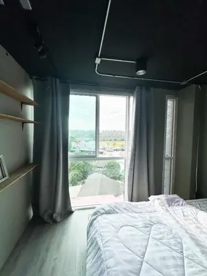 a bedroom with a bed and a large window at Bukitta Airport Condominium by Sutanee in Ban Bo Han