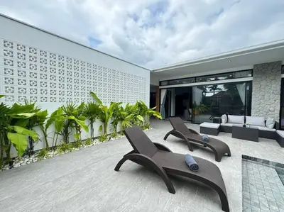 an outdoor patio with two chairs and a building at Luciana Villa by G Estate Phuket in Rawai Beach