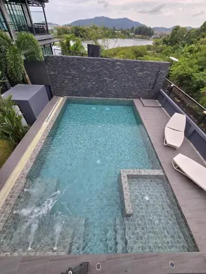 a swimming pool with two chairs on a deck with at Kathu V pool villa 171 in Kathu