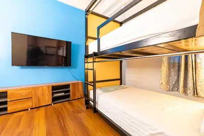 a bedroom with two bunk beds and a flat screen tv at Queen On Street Guest House in Ban Lo Long