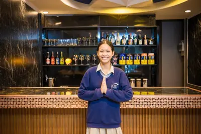 a woman is standing in front of a bar at Queen On Street Guest House in Ban Lo Long