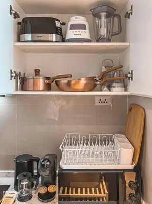 a kitchen with a shelf with dishes and utensils at 5 Star La Vita Studio Rawai 702 in Phuket Town