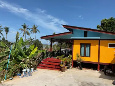 a yellow house with a red staircase in front of it at Baan Suan Sunset in Ban Laem Sai