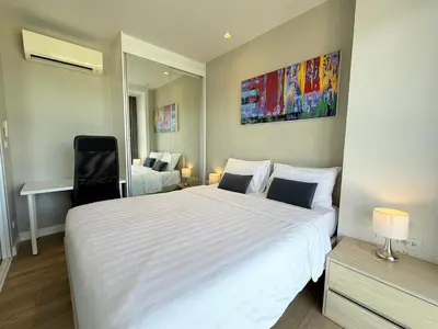 a bedroom with a large white bed and a chair at Diamond Resort Phuket Condo Bang Tao Beach in Thalang