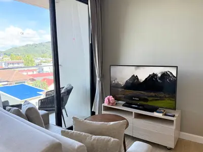 a living room with a flat screen tv and a couch at Diamond Resort Phuket Condo Bang Tao Beach in Thalang