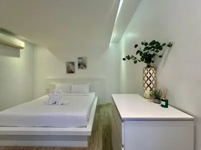 a white room with a bed and a vase of flowers at The Sense Villa Phuket in Rawai Beach