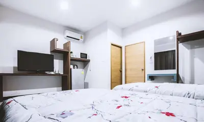 a bedroom with two beds and a flat screen tv at Ra Residence Phuket in Chalong