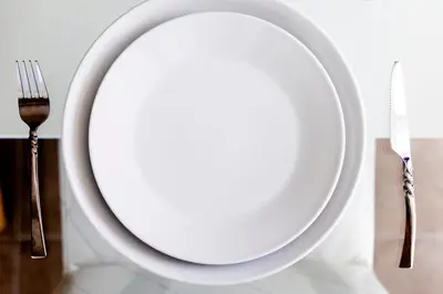 a white plate on a table with a fork and knife at ELEGANT Kata sea View Apartmens in Kata Beach